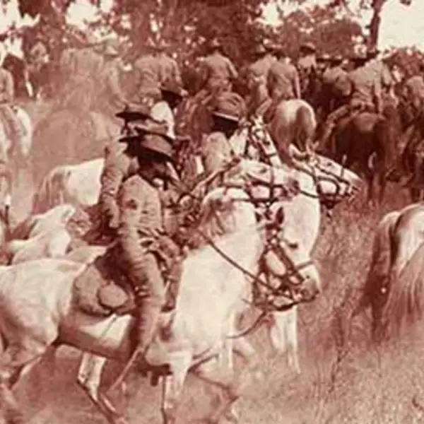 A busy tinted historical photo of cowboys on horses.