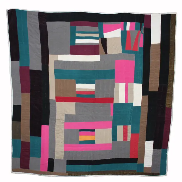 A colorful quilt created with rectangular panels in dark-neutral tones, blue-green, and neon pink.