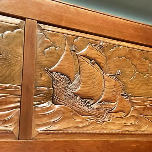 A detail view of a carved wood panel depicting a ship at sea.
