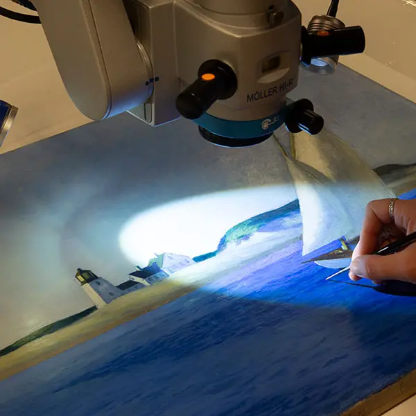 A microscope light illuminates a section of a painting.