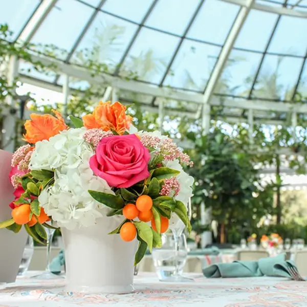 A flower arrangement on a table under a glass dome.