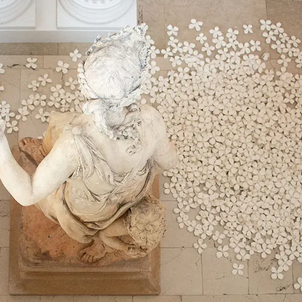 statue on gallery floor with flowers at base