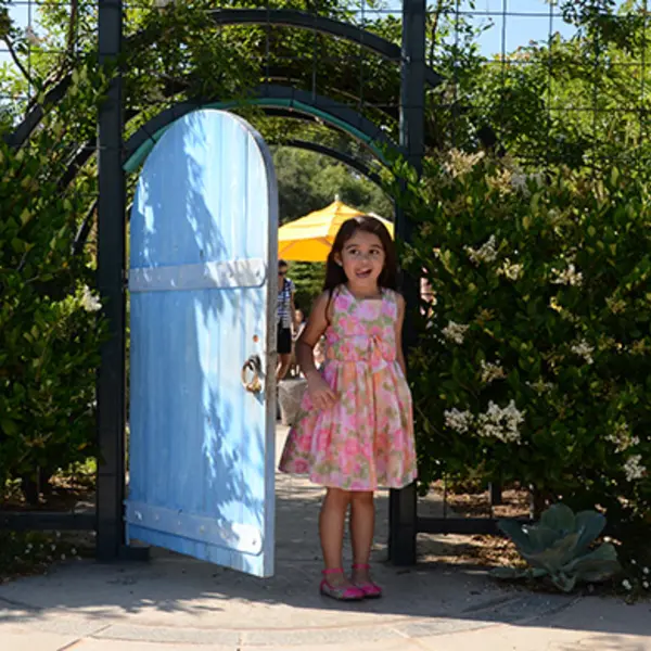 Girl by a blue door in the Childrens Garden