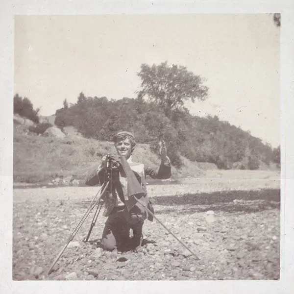 Jack London kneels by his camera in ca. 1900
