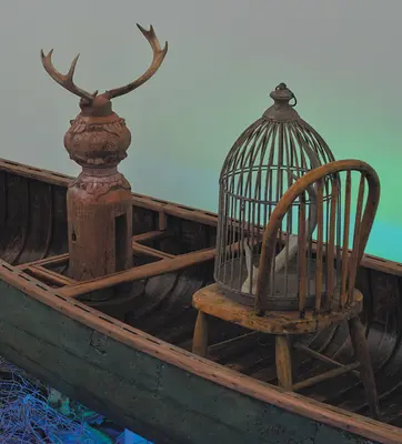 Detail view of an immersive art installation with a wooden canoe and various found objects.