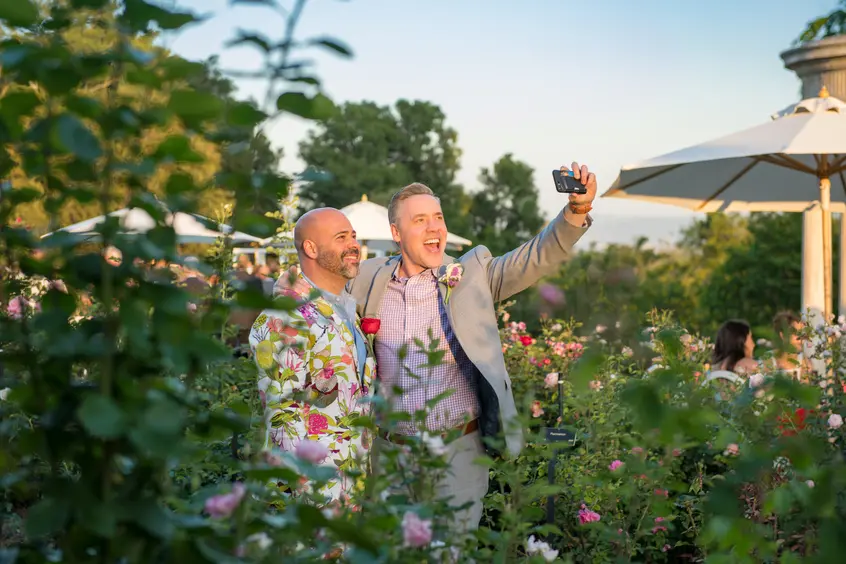 Two people take a selfie among roses.