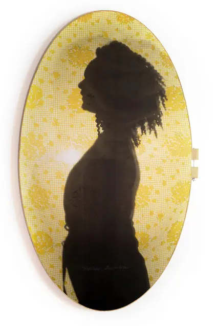 A side-profile silhouette of a person with curly hair, against a backdrop of yellow lace.