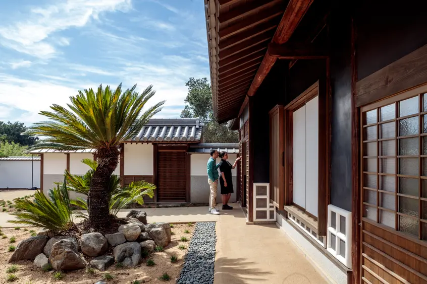 Visitors stand at the front entrance courtyard of a traditional Japanese home.