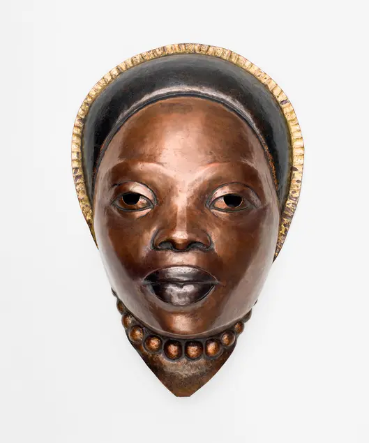 A copper mask of a woman with a headdress and necklace.