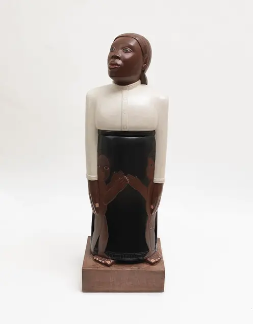 A carved and painted wood sculpture of a woman looking up.