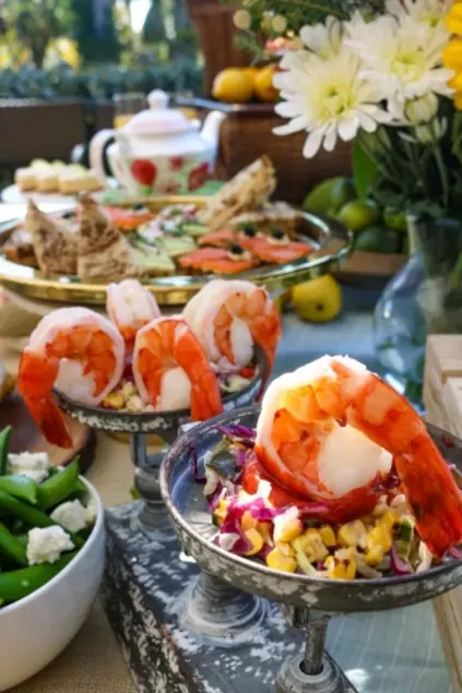 A buffet with various dishes, shrimp is in the foreground.