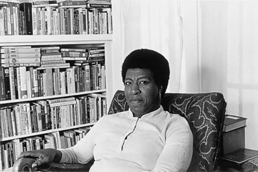 Octavia Butler seated by her bookcase