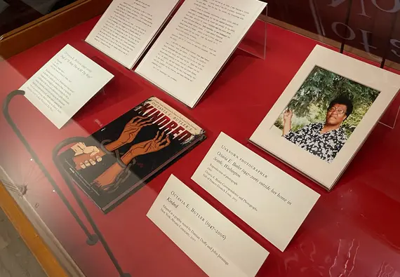 Overhead view of a book, photograph, and text documents in a glass display case.