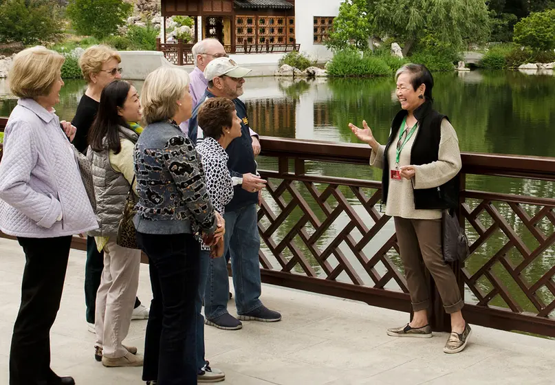 A tour guide talks to a group of people near a lake.
