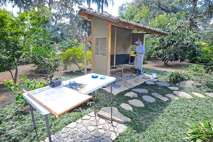 As part of periodic maintenance, the tea garden’s machiai or waiting bench received new rice paper to line its walls. Kyoto landscape designer Takuhiro Yamada consults his notes. Photo by Andrew Mitchell.