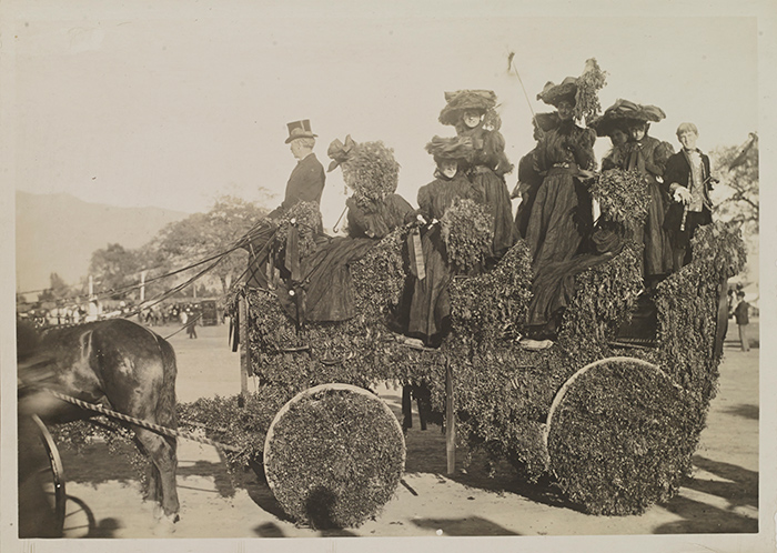 A gentleman in a top hat drives a decorated carriage of ladies in dark dresses in what appears to be Tournament Park, at the end of the parade route, 1905. Jack London Collection. The Huntington Library, Art Collections, and Botanical Gardens.