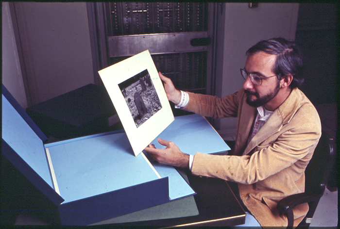 Alan Jutzi in the rare book stacks perusing a photograph by Edward Weston, circa 1980.