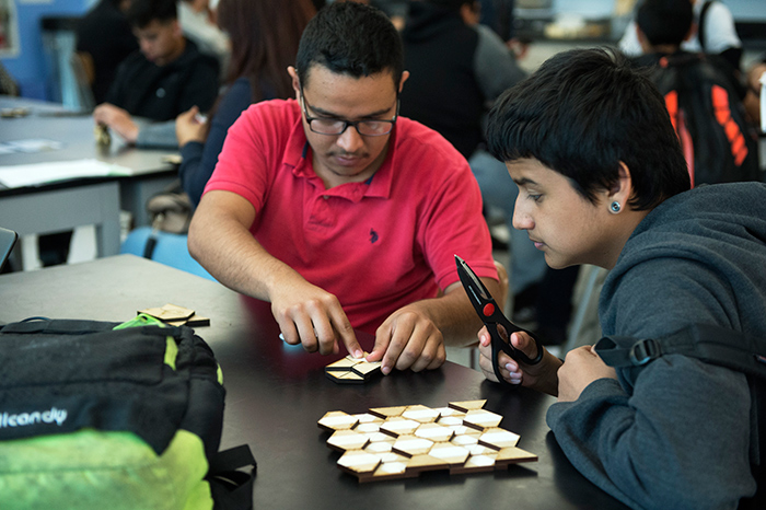 Students attached wooden tiles with cloth tape to create a Miura-Ori model, an example of which is seen in the foreground. Photo by Martha Benedict.