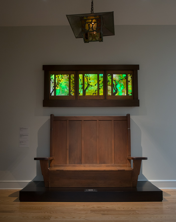 A bench, art glass window, and porch lantern in the entry foyer make it hard to miss the Greene & Greene collection.