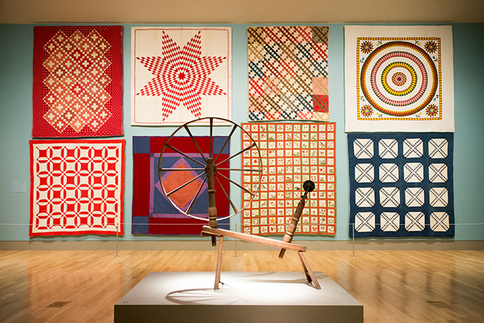 This selection of quilts, made between 1850 and 1900, includes a wide variety of styles and patterns. The spinning wheel in the foreground dates from the early 18th century. Jonathan and Karin Fielding Collection. Photo by Kate Lain.