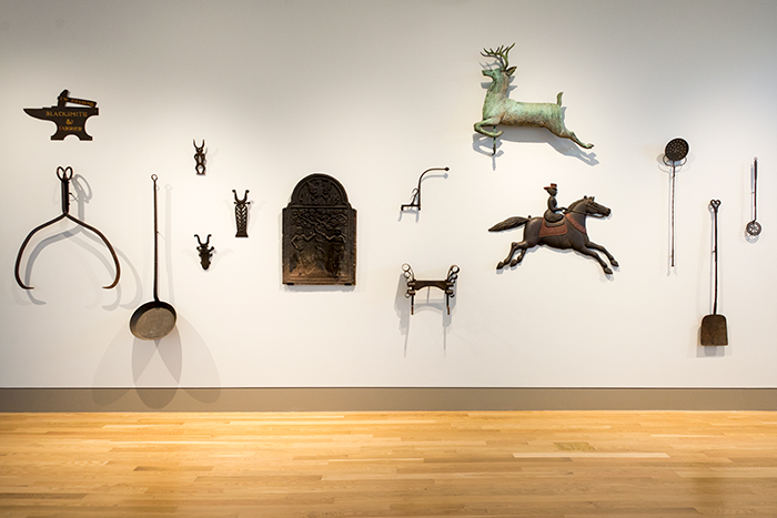 The wall along the entryway into the Fielding Wing displays useful implements made of metal, including ice tongs, bootjacks, and long-handled tools for the fireplace. Jonathan and Karin Fielding Collection. Photo by Kate Lain. 