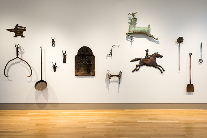 The wall along the entryway into the Fielding Wing displays useful implements made of metal, including ice tongs, bootjacks, and long-handled tools for the fireplace. Jonathan and Karin Fielding Collection. Photo by Kate Lain.