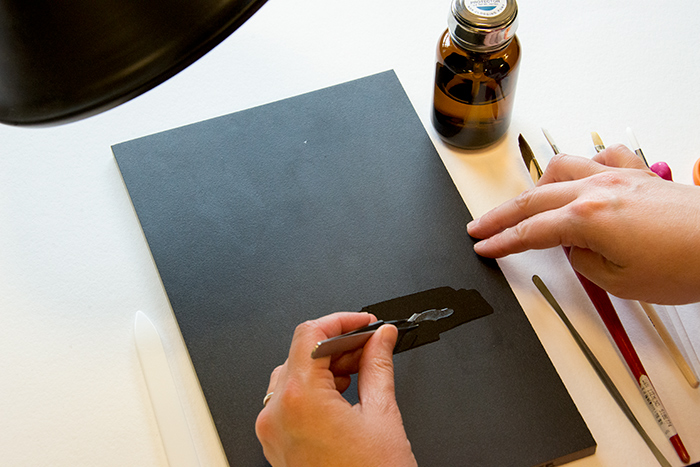 Westberg brushes Ethanol on a black tile to insure even application of the solvent and to help her see the nearly transparent repair piece. Photo by Kate Lain.