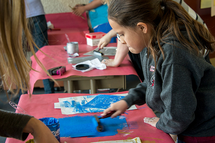 Children in Pam Chirichigno’s fifth-grade class at Rockdale learned how to make prints of their alien worlds by etching a design onto a sheet of styrofoam. Here, Denise Eichenauer applies ink to a roller. Photo by Kate Lain.