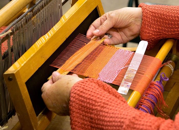 Weaving on a table loom. Photo by Deborah Miller.