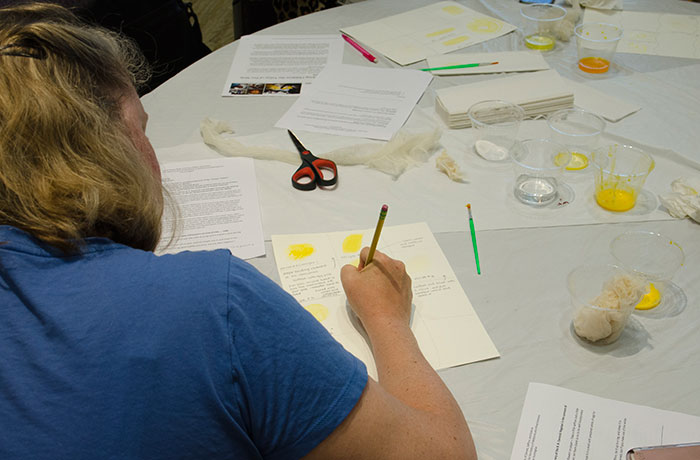 Tracy Clark, a teacher from Torrance High School, takes notes on each shade of yellow and how it was made, and records differences in outcomes due to recipe variations. Photo by Lisa Blackburn.