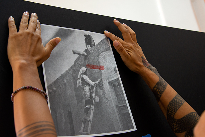 Caycedo, in her studio, attaching a photographic copy gathered from her research to a presentation screen. Photo by Kate Lain.