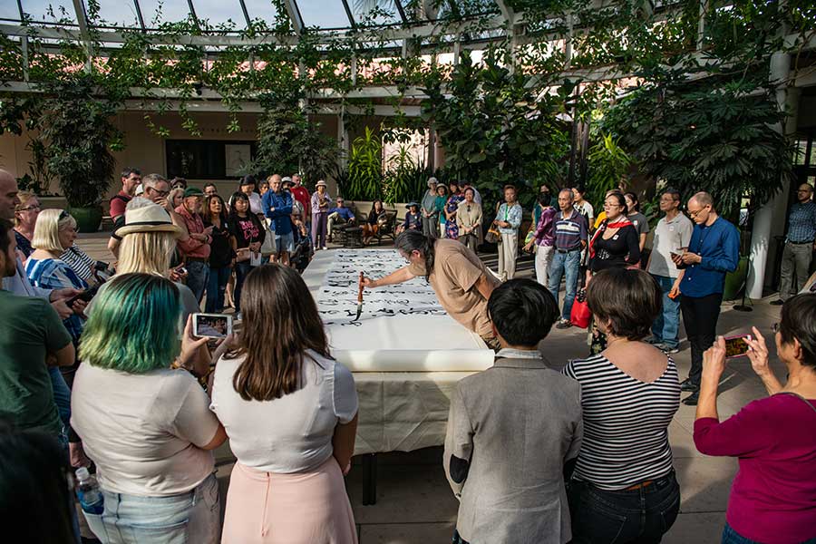 Tang Qingnian brushed the poem, titled “Song of Eight Drinking Immortals,” onto an unfurling, 40-foot blank page in the Rose Hills Garden Court. Photo by Jamie Pham.