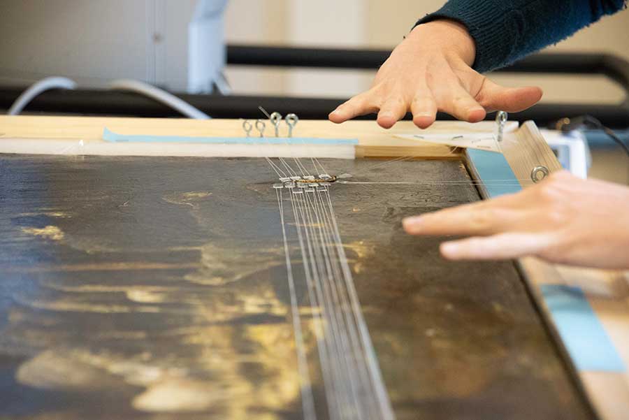 Kari Rayner, Andrew W. Mellon Fellow in Paintings Conservation at the National Gallery of Art in Washington, D.C., uses a stretching device called a trecker to repair a tear in Charles Émile Jacque’s Interior, Sheep and Shepherd (ca. 1875) at The Huntington. Photo by Deborah Miller.