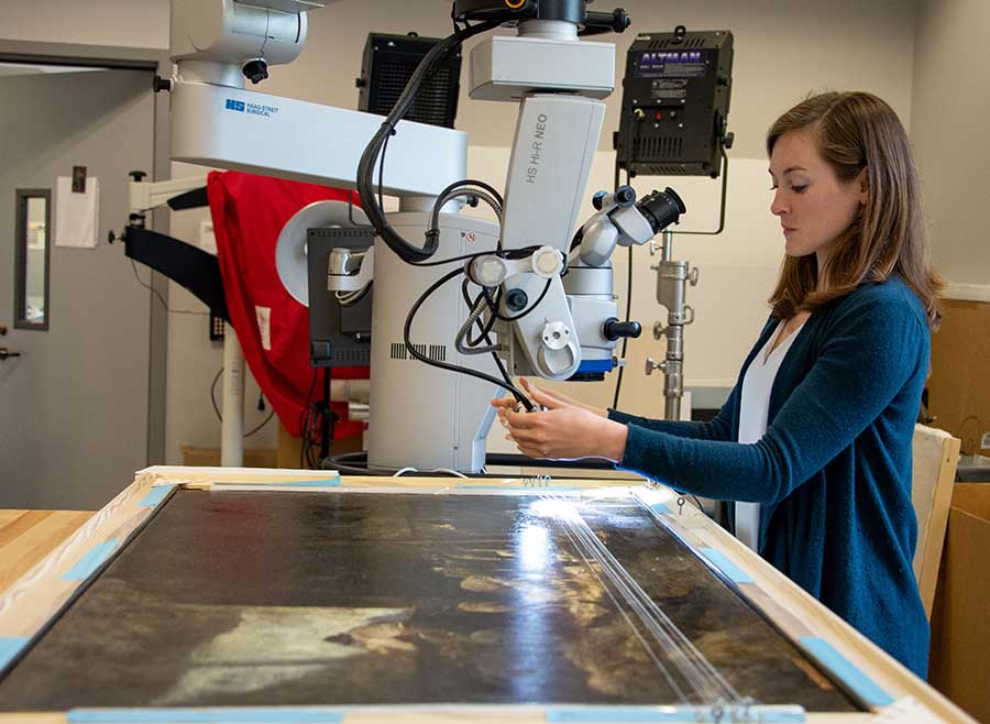 Kari Rayner, Andrew W. Mellon Fellow in Paintings Conservation at the National Gallery of Art in Washington, D.C., adjusts microscope lighting before viewing a tear in Charles Émile Jacque’s Interior, Sheep and Shepherd (ca. 1875) at The Huntington. Photo by Deborah Miller.