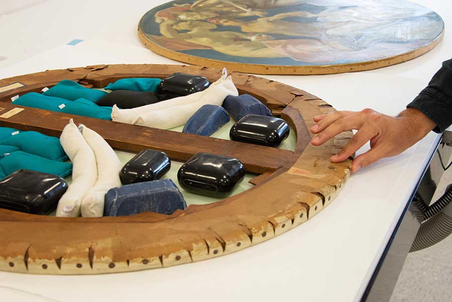 After carefully examining and testing Sargent’s Sphinx and Chimera with moisture, it was determined that the painting could withstand the proposed treatment. The painting is shown here facedown on a worktable. Note the notched canvas along the tacking edge, elucidating Sargent’s technique. Photo by Deborah Miller.